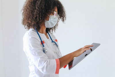 A Doctor Wearing a Face Mask Using a Tablet